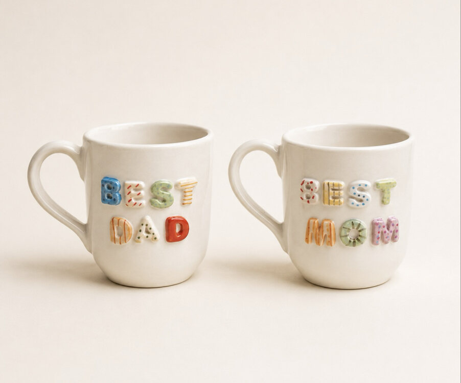 Renkli kabartma harflerle BEST DAD ve BEST MOM yazılı iki beyaz seramik kupa